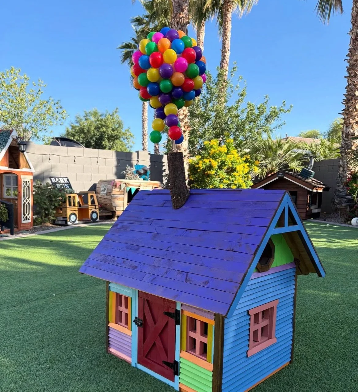 Colorful dog house topped with a bright balloon display